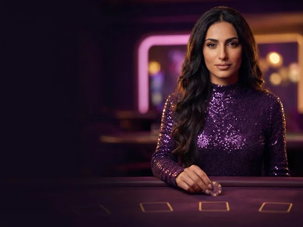 Lobby-style demo game card: portrait crop of the croupier at a purple table, holding a chip between two fingers